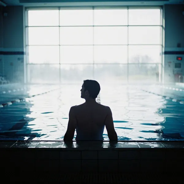 A swimmer silhouetted at the edge of an indoor pool